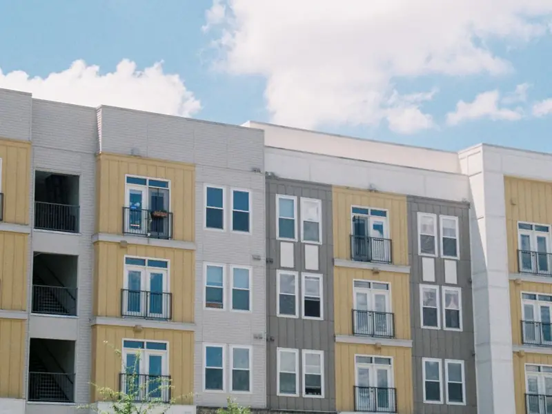 A modern apartment building with yellow and grey balconies under a blue sky